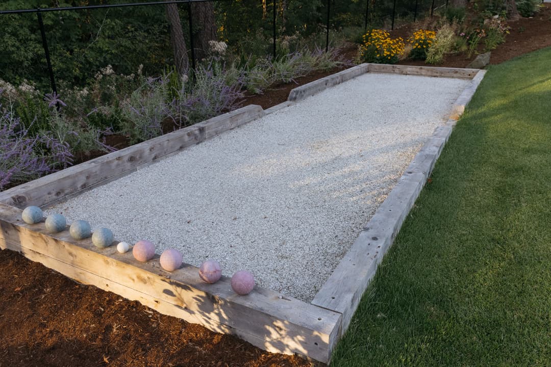 Bocce ball court with gravel surface and colorful balls lined up on the edge.