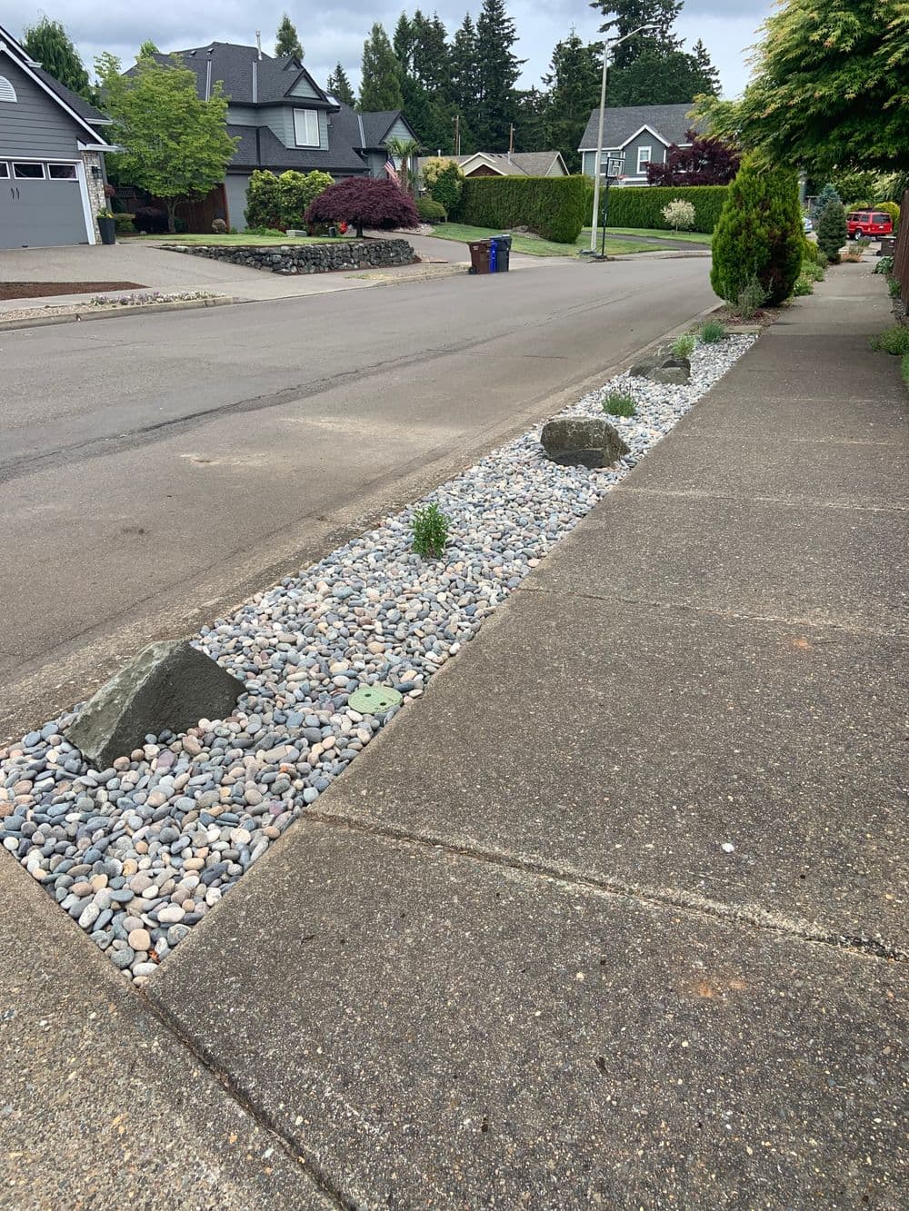 Street view featuring a decorative gravel landscape with small plants and rocks along the sidewalk.