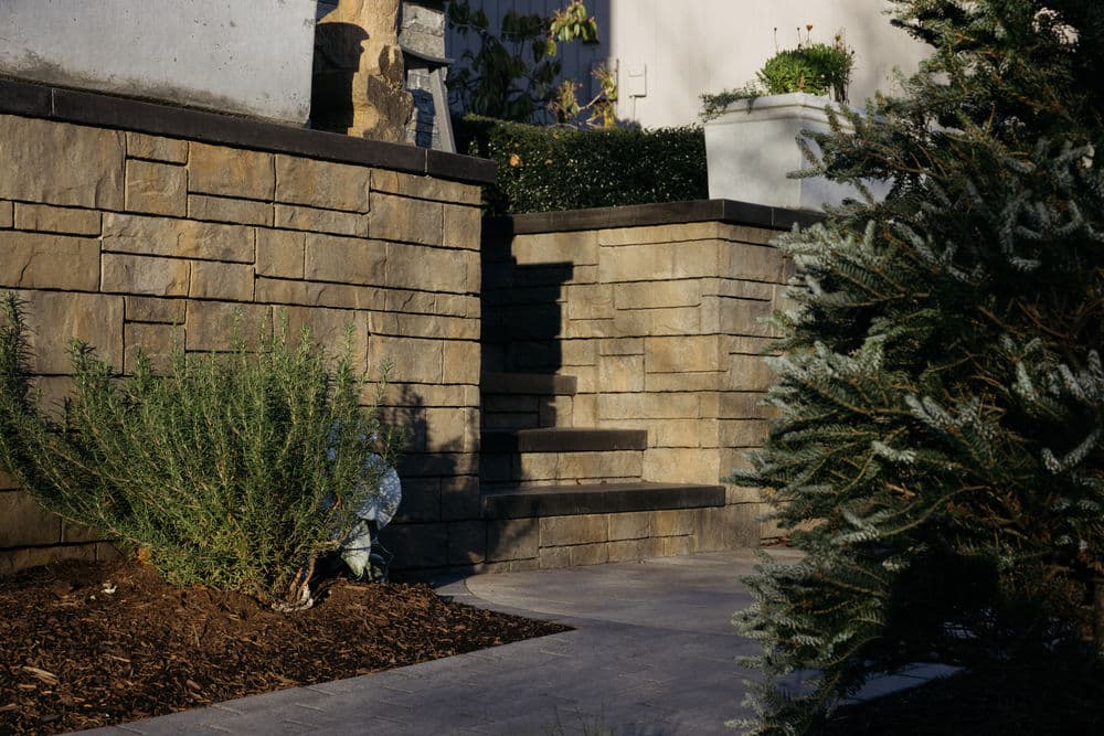 Stone steps leading up in a landscaped garden with greenery and decorative plantings.