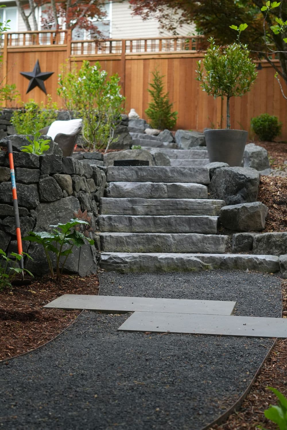 Stone steps lead up through a landscaped garden with wooden fencing and decorative plants.
