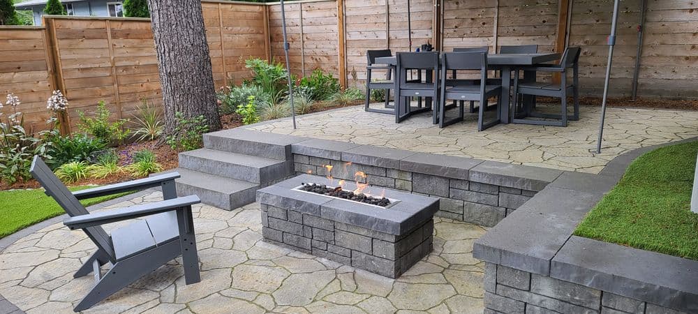 Modern outdoor patio with seating, fire pit, and wooden fencing for relaxation and entertainment.