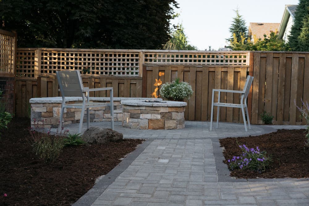 Cozy outdoor seating area with a fire pit, stone seating, and landscaped garden elements.