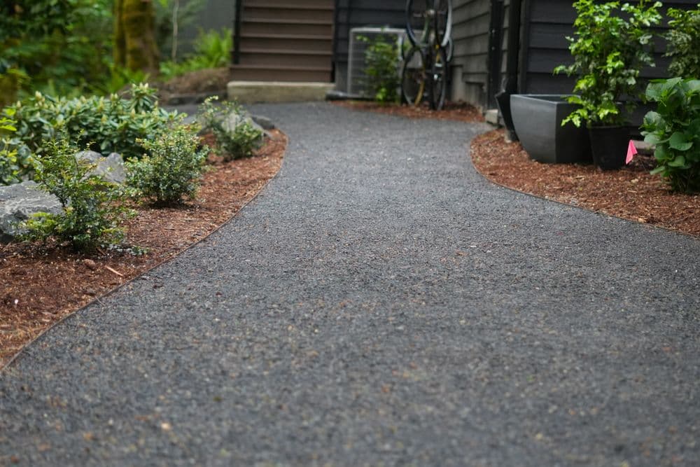 Winding gravel pathway in a landscaped garden with greenery and plants.