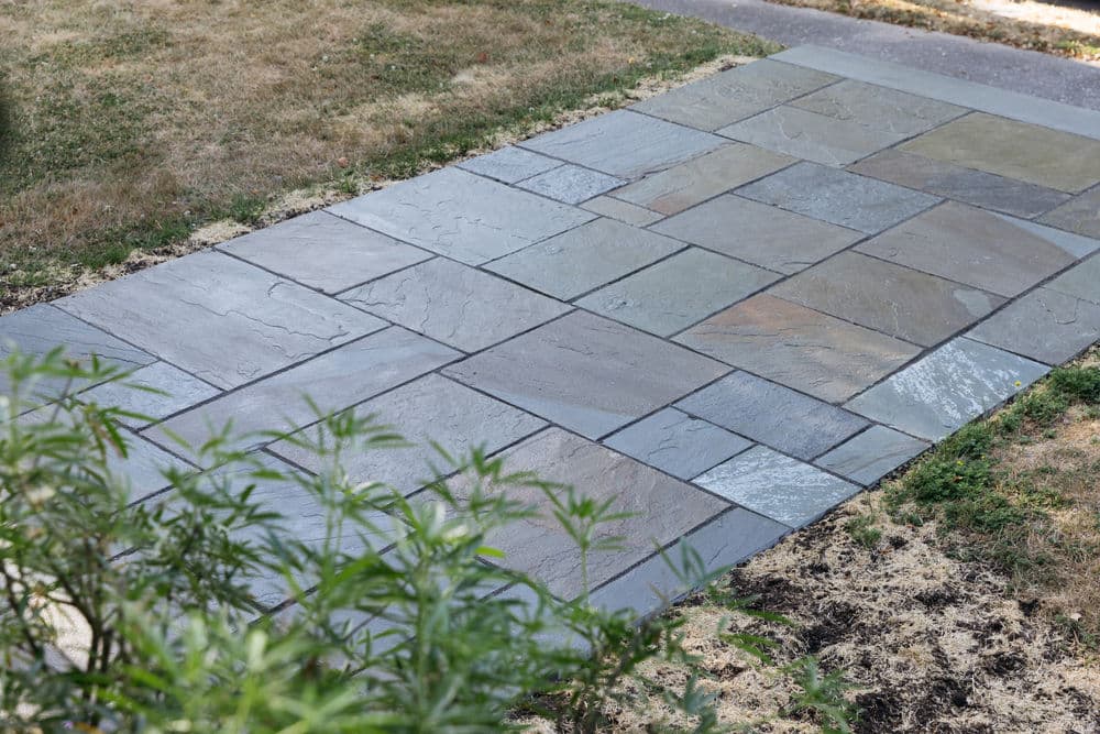 Stylish stone pathway made of flat slate tiles in a grassy yard setting.