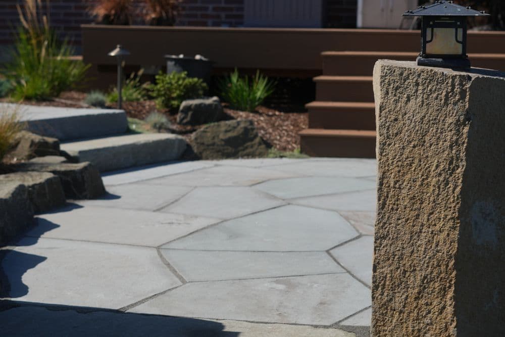 Patio with stone paving, decorative lanterns, and landscaped garden elements.